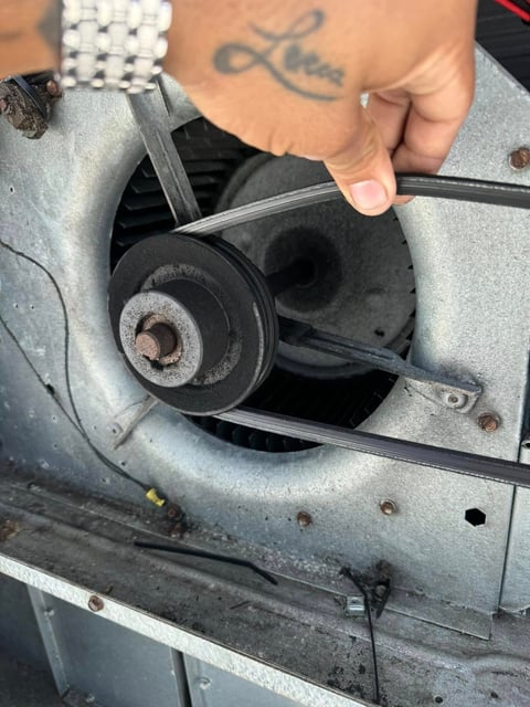 Persons hand holding a pulley or belt component from an automotive engine, showing internal mechanical parts and corrosion